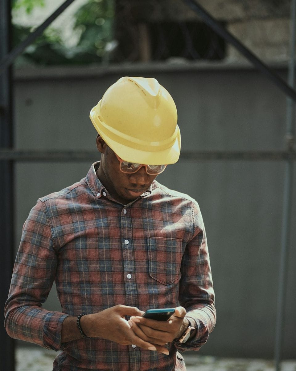 Contractor in a hard hat taking a lead on his phone